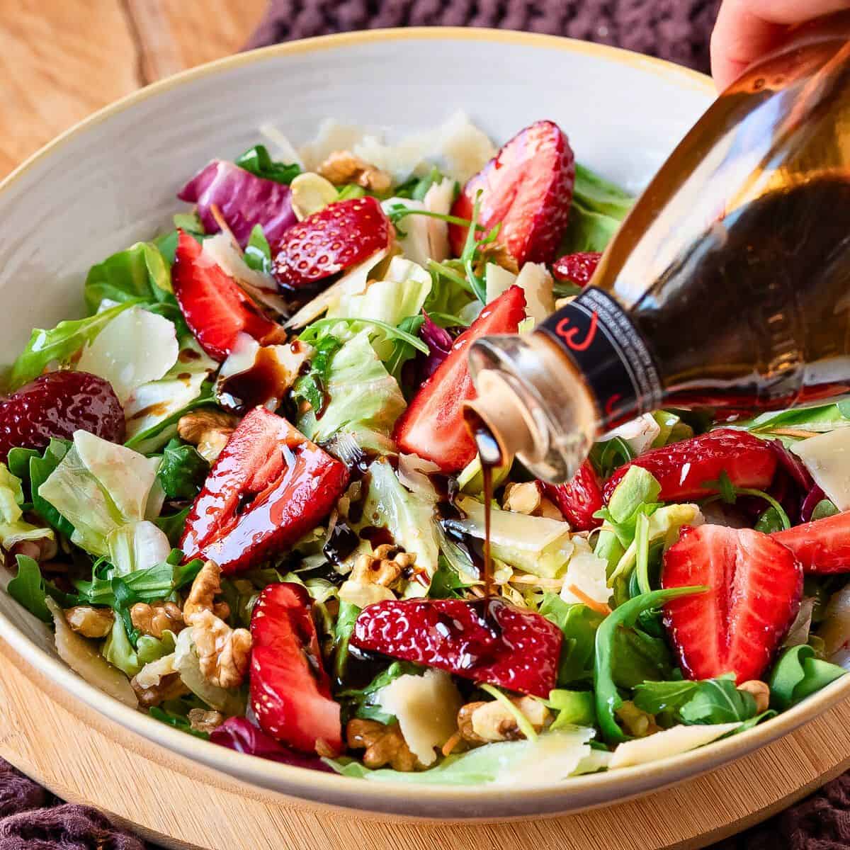 Pouring aged balsamic vinegar over the salad.
