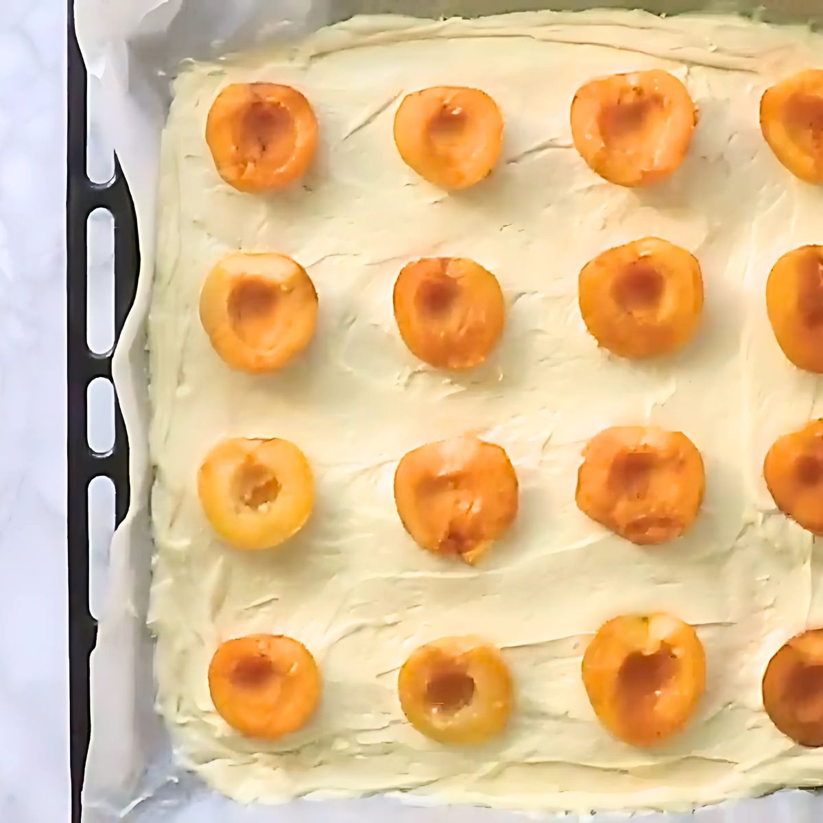 Placing apricot halves into the batter on the sheet pan.