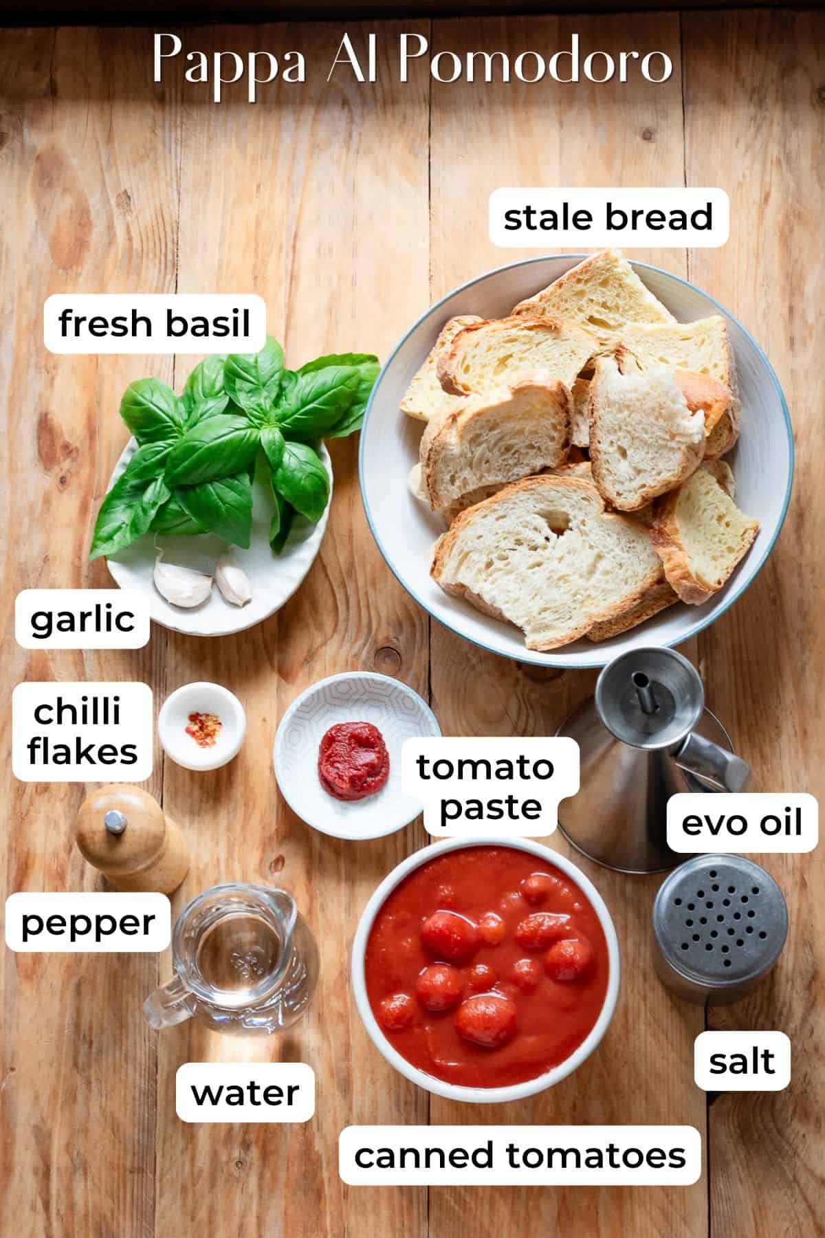 Ingredients needed for pappa al pomodoro laid on a wooden surface.