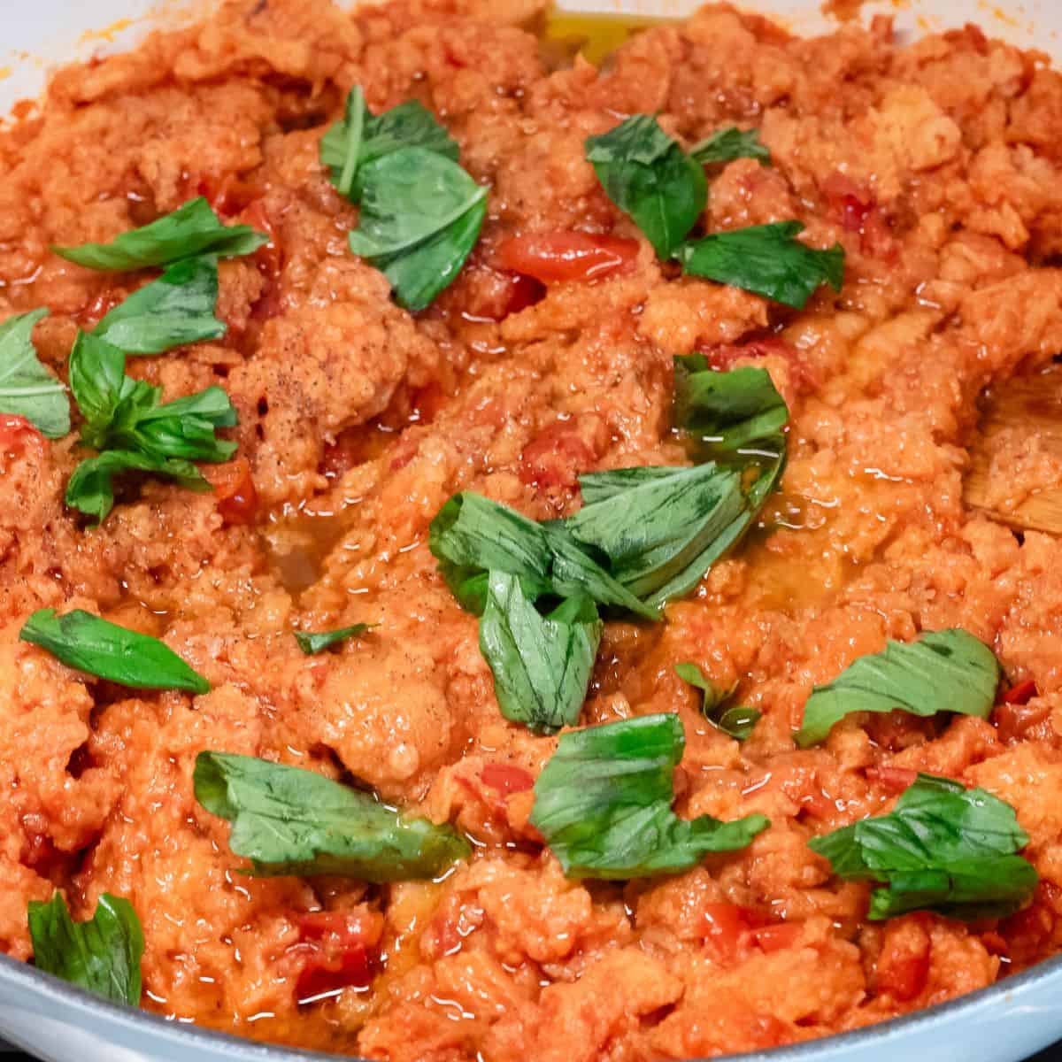 Adding torn basil leaves to pappa al pomodoro.