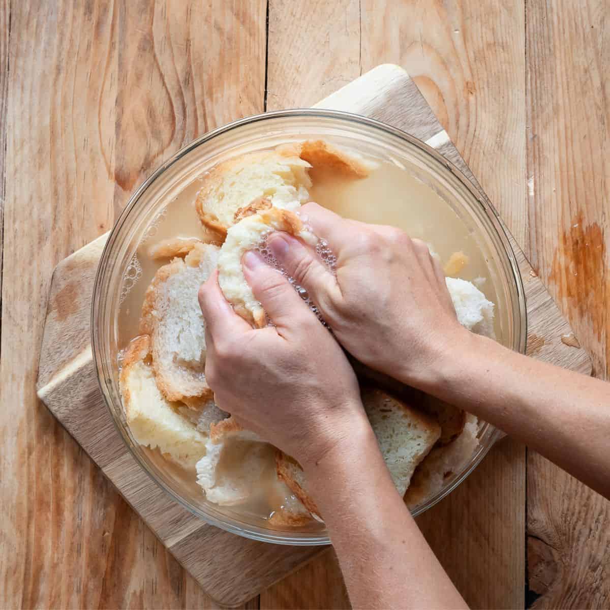 Squeezing soaked bread with hands.