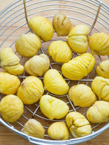 Boiled chestnuts in a metal steaming basket.