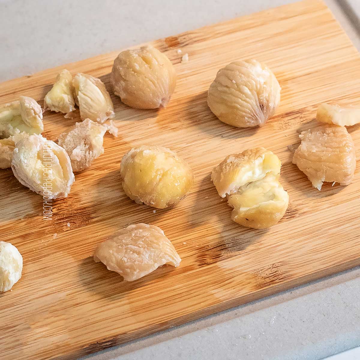 Boiled chestnuts peeled on a wooden board.