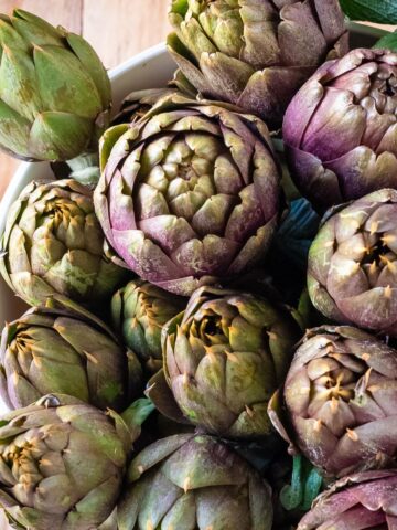 Fresh artichokes in a bucket with water.