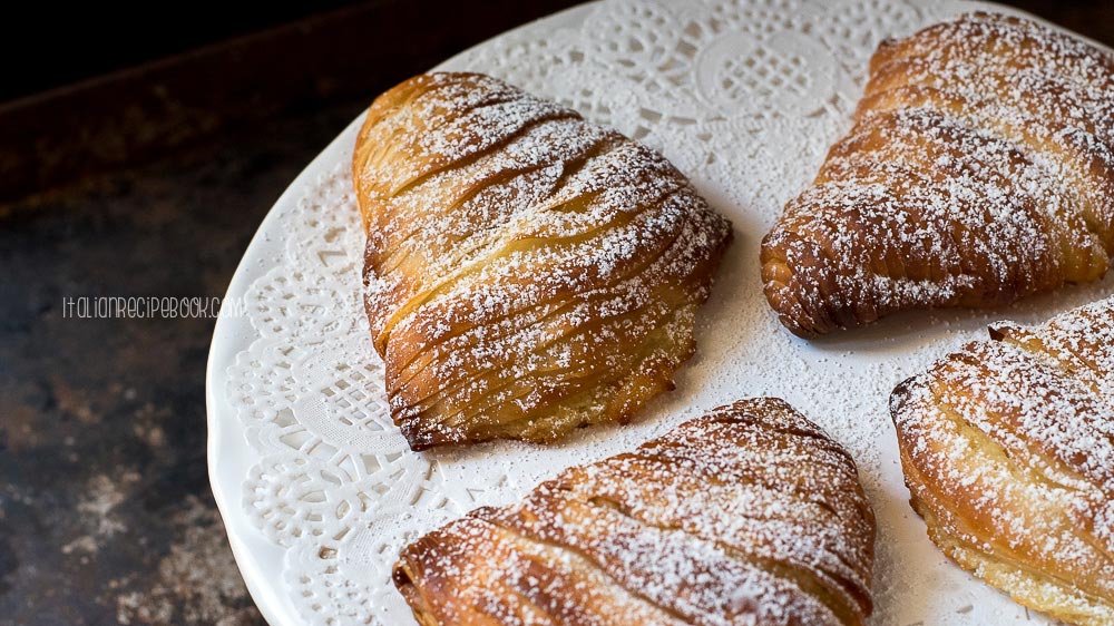 sfogliatelle dusted with confectioners sugar on a white plate