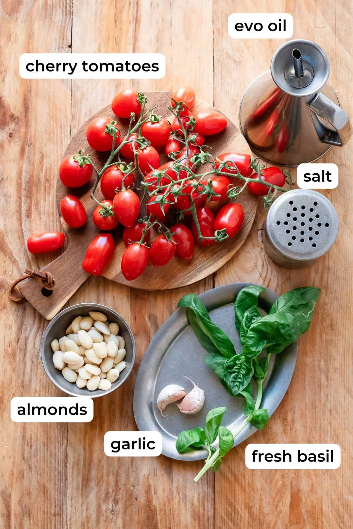 Ingredients needed for pesto trapanese laid on a wooden surface.