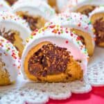 Cuccidati cookies with fig filling topped with icing and sugar sprinkles.