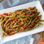 green beans in tomato sauce on a white serving plate