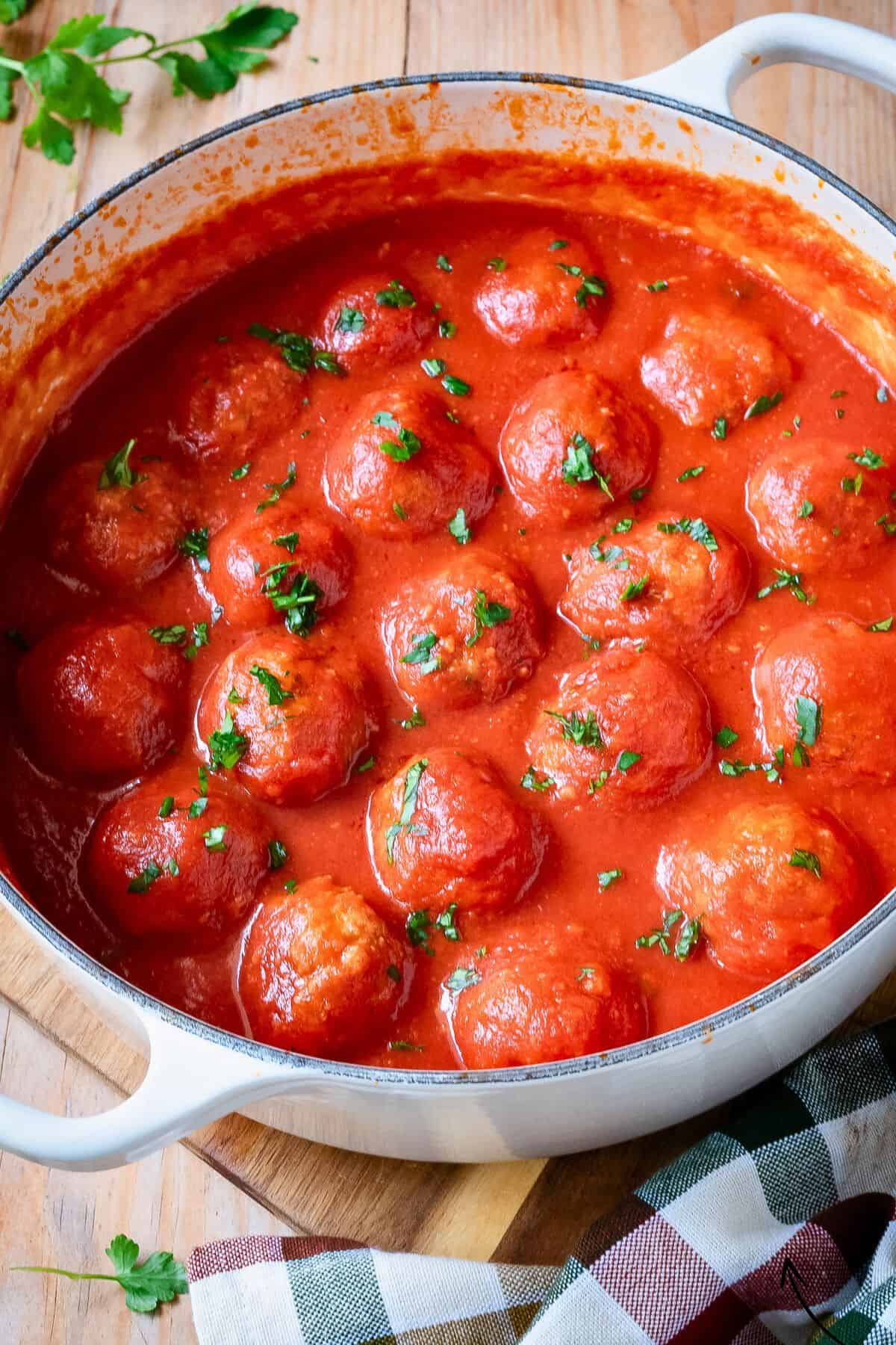 Italian meatballs in tomato sauce in a white pot.