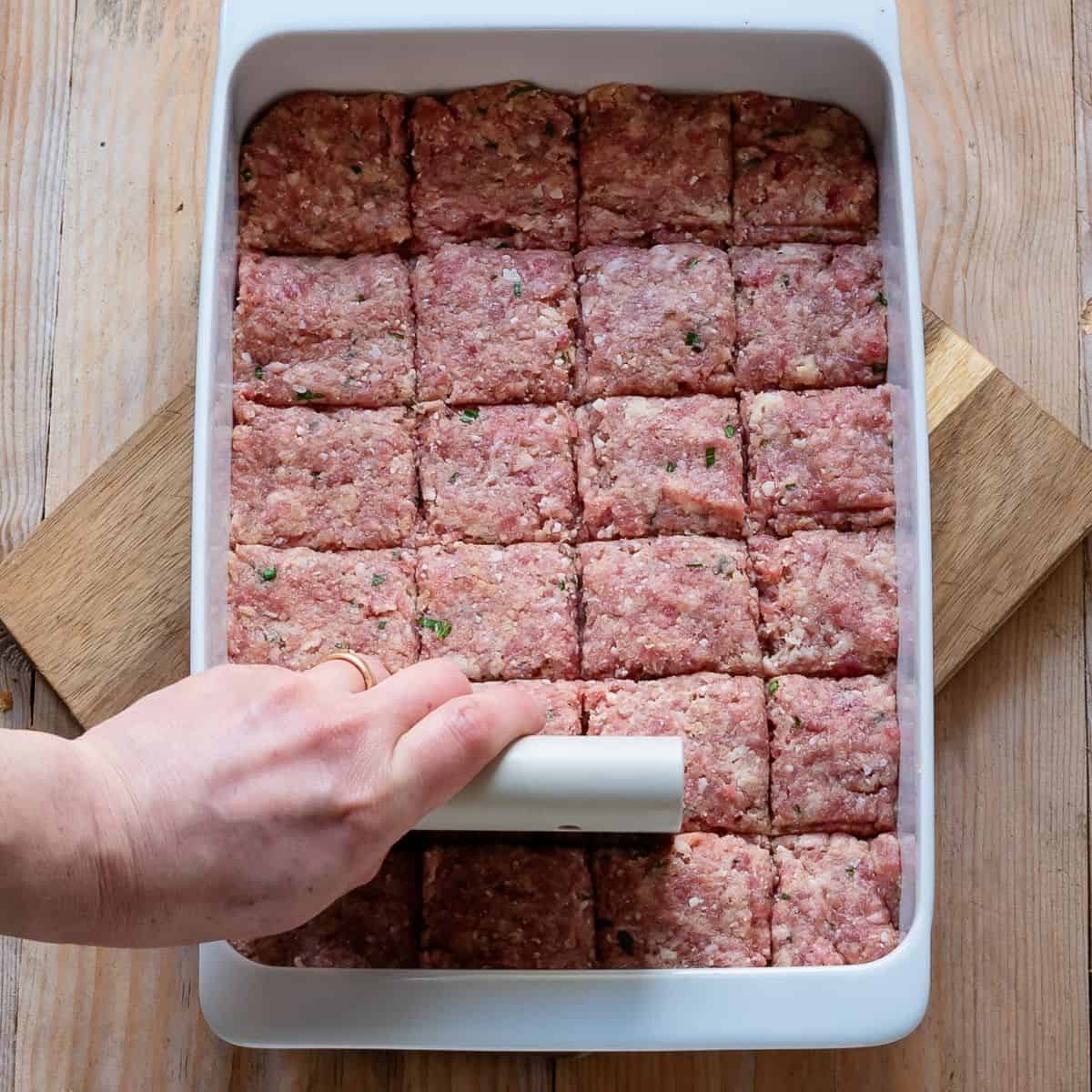 Dividing polpette mix into squares using a bench scraper.