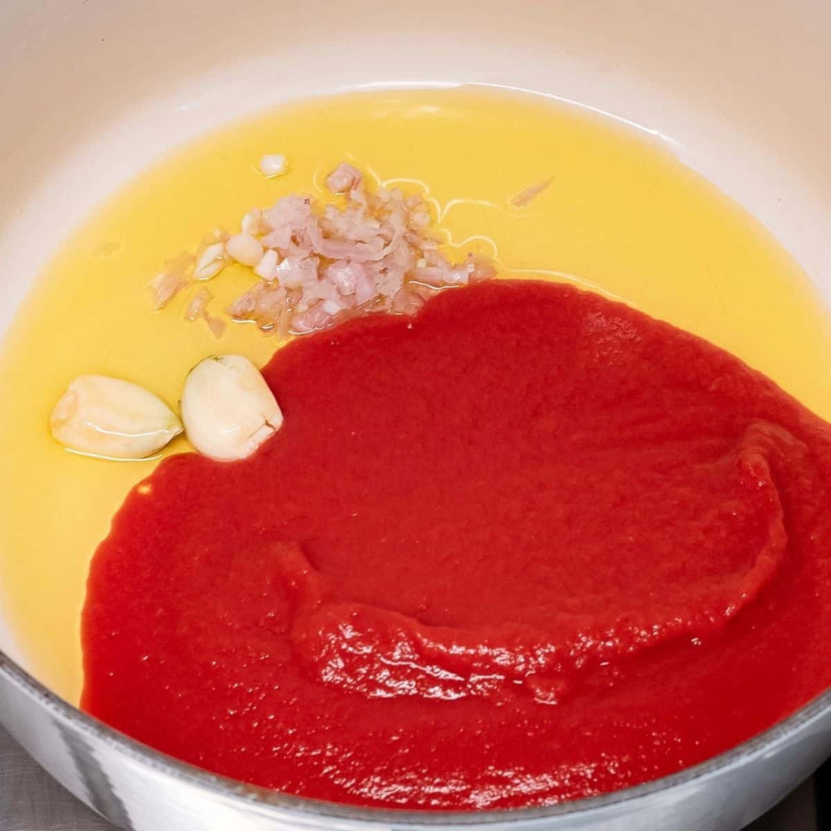 Olive oil, garlic, shallot and tomato passata in a casserole.