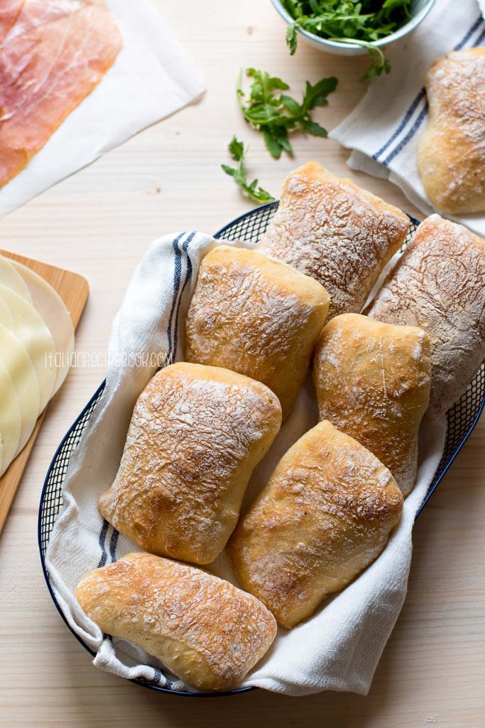 Ciabatta rolls in a bread basket on the wooden table.