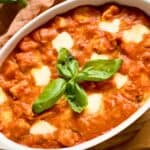 Chicken Sorrentino in a casserole garnished with basil leaves.