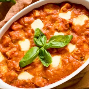 Chicken Sorrentino in a casserole garnished with basil leaves.