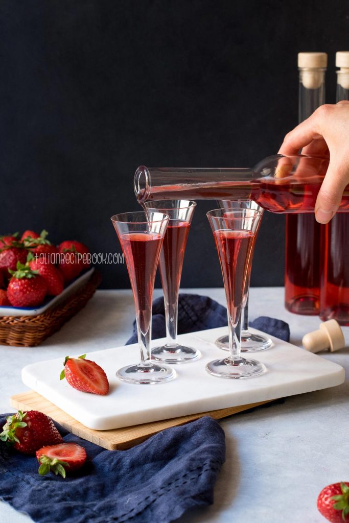 Pouring strawberry liqueur in liqueur serving glasses.
