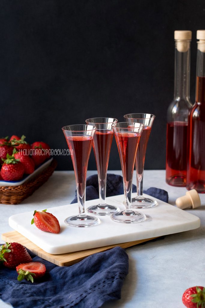 Homemade strawberry liqueur in liqueur glasses on a marble tray.