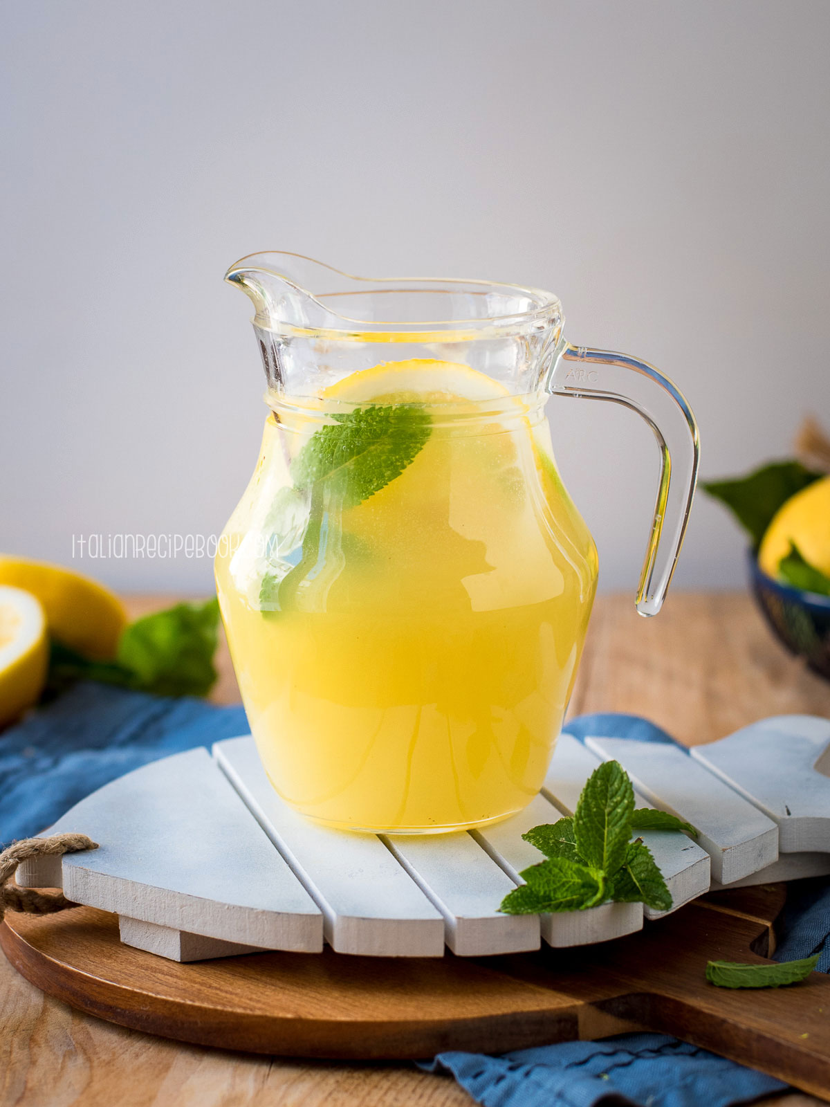 A pitcher of lemonade on a wooden board.