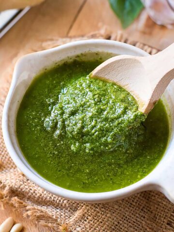 Creamy basil pesto scooped with a wooden spoon.