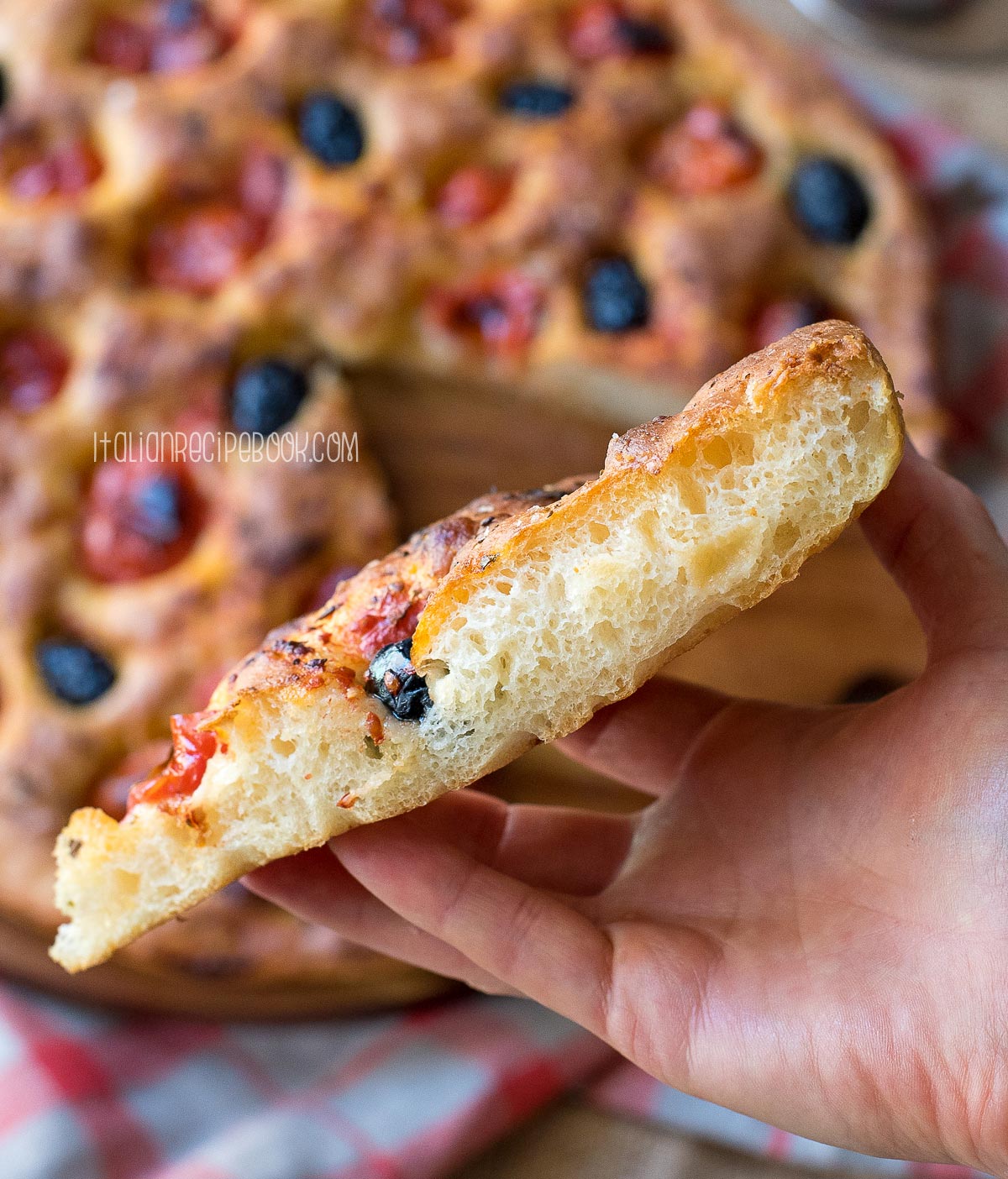 holding a piece of focaccia in hand