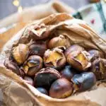 roasted chestnuts in a paper bag with lights in the background