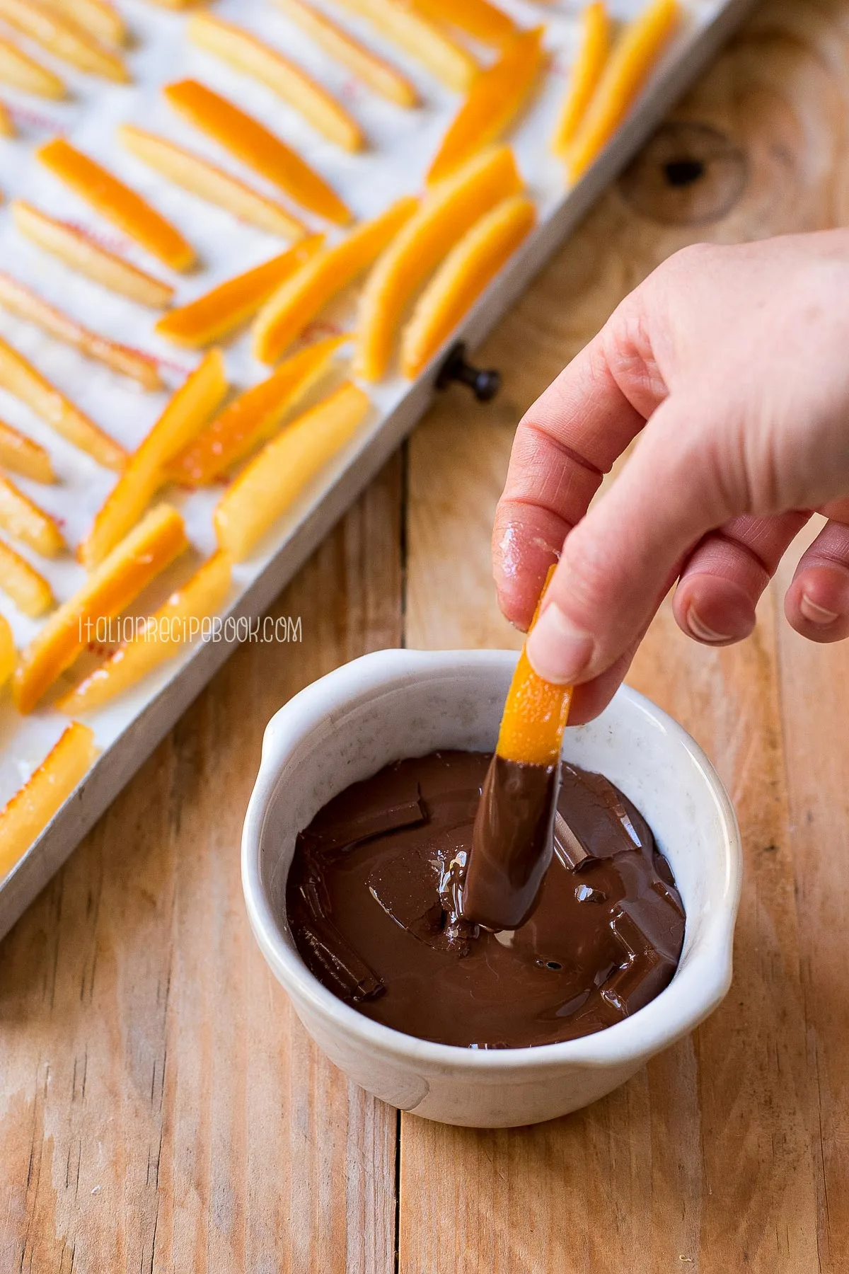 hand dipping orange peels in dark chocolate