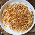 Spaghetti with breadcrumbs on a round plate.