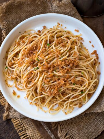 Spaghetti with breadcrumbs on a round plate.