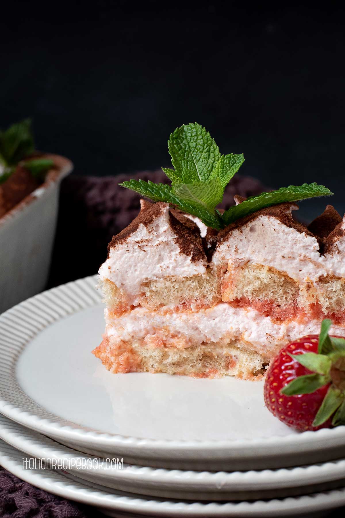A piece of strawberry tiramisu on a plate.