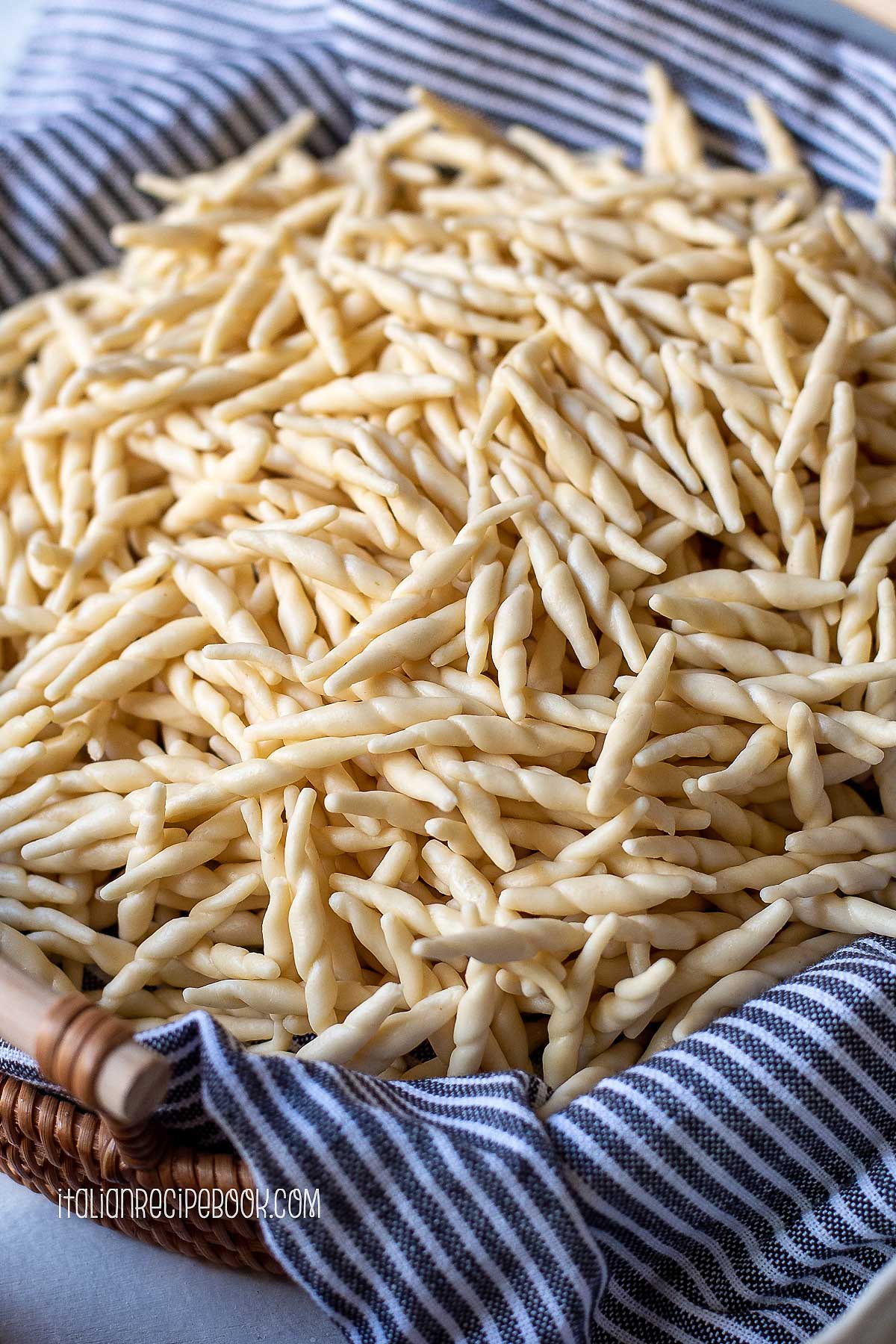 Trofie pasta in a basket lined with a linen towel.