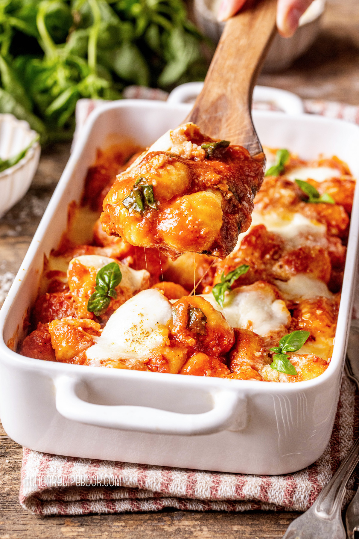 Scooping gnocchi alla sorrentina with a wooden spoon.