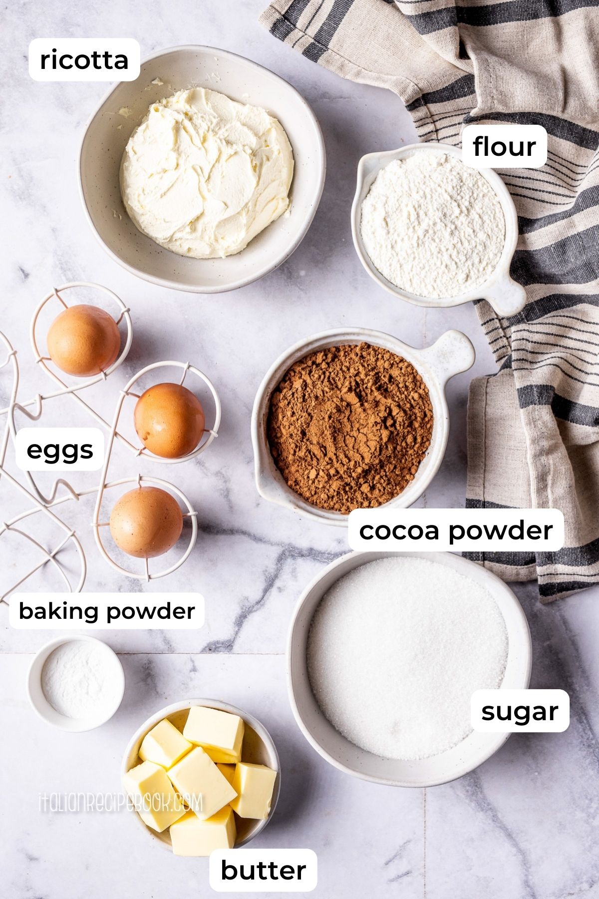 Ingredients needed to make chocolate ricotta cake laid on a marble surface.