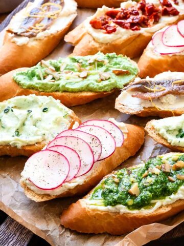 Whipped ricotta crostini with assorted toppings on a tray.