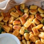 Fried gnocchi with rosemary in a serving dish.