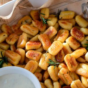 Fried gnocchi with rosemary in a serving dish.