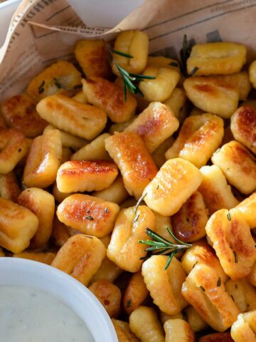 Fried gnocchi with rosemary in a serving dish.