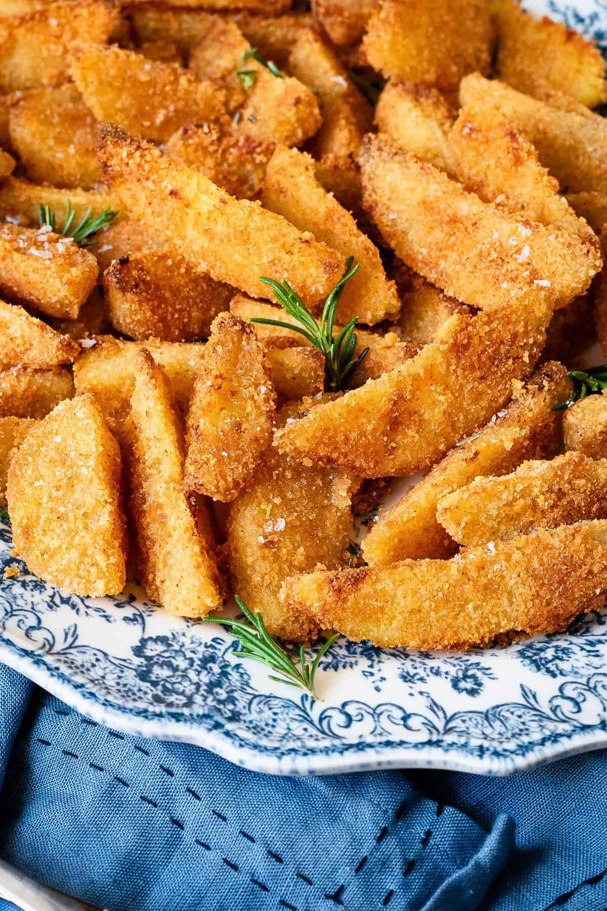Parmesan potatoes on a serving plate with a blue rim.