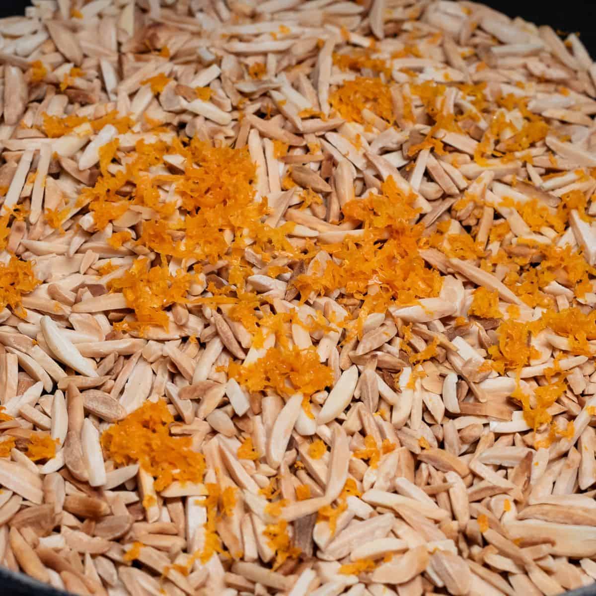 Adding orange zest to toasted almonds.