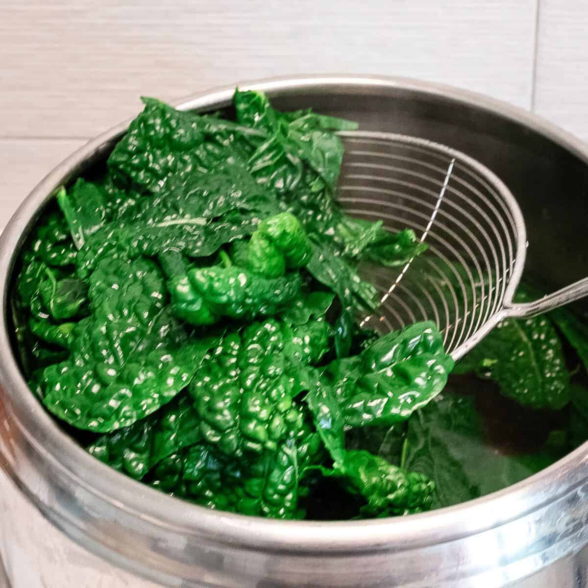 Removing kale leaves from boiling water.