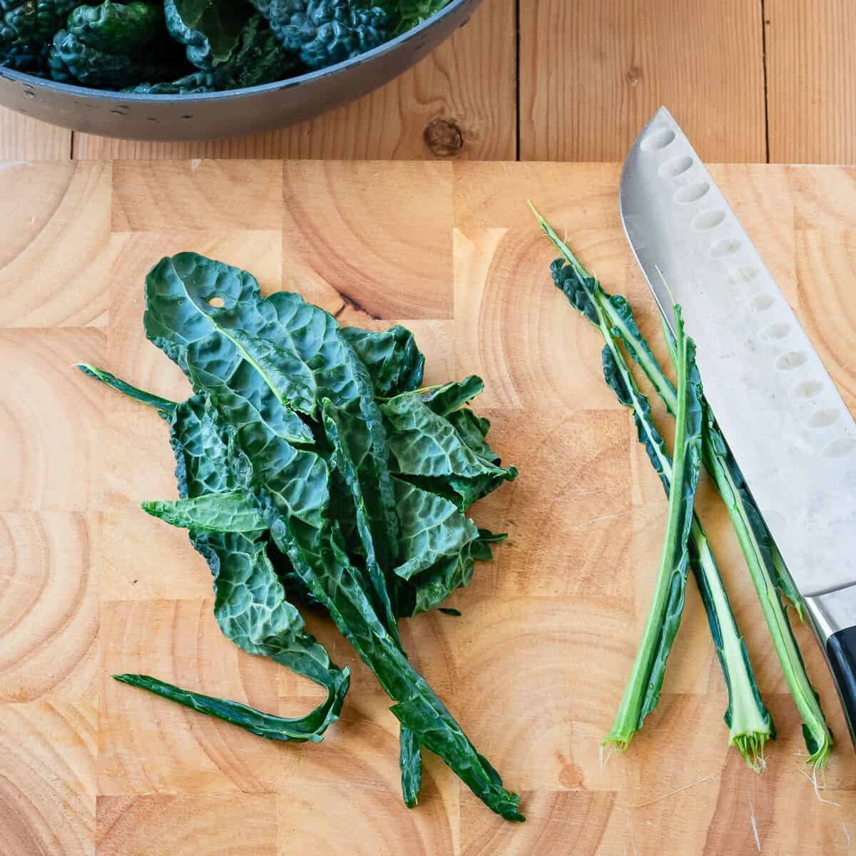 Trimmed kale leaves of a wooden board.