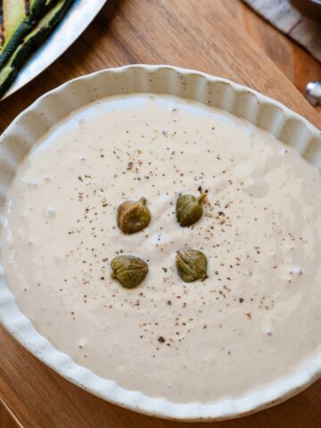 Salsa tonnata in a rimmed bowl, garnished with capers.