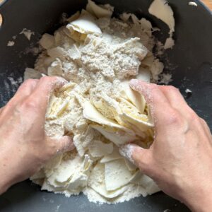 Tossing frozen butter shavings with flour by hand.
