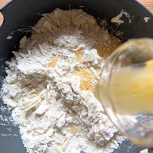 Pouring egg and water mixture into flour and butter shavings.