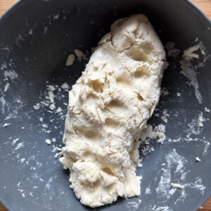 Shaggy puff pastry dough compacted into a rough log in a bowl.