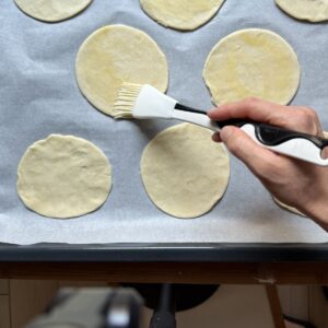Brushing puff pastry with egg wash.