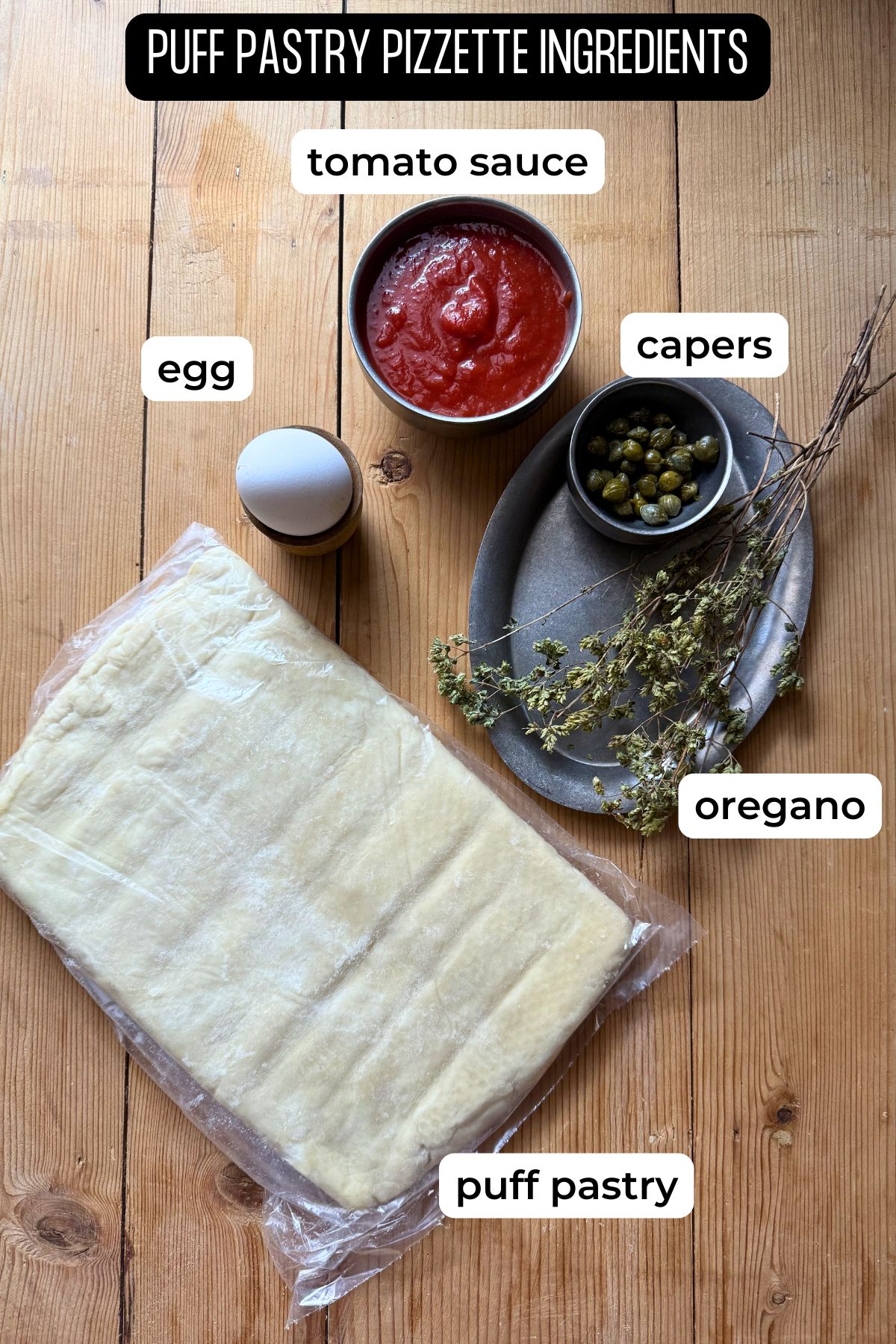 Ingredients for puff pasty pizzette laid on a wooden surface.
