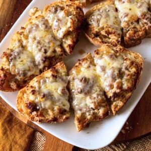 Baked sausage crostone on a white platter.