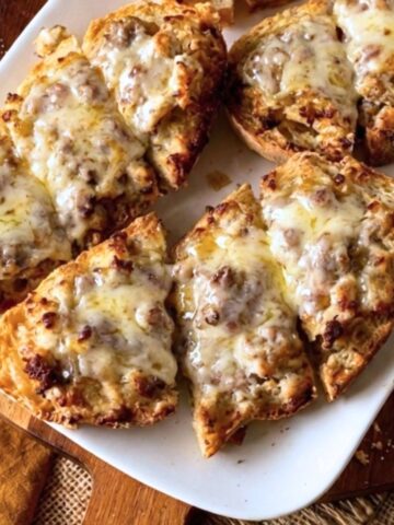 Baked sausage crostone on a white platter.