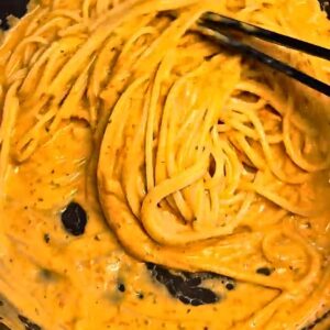 Spaghetti tossed in creamy roasted tomato sauce until glossy in a pan.