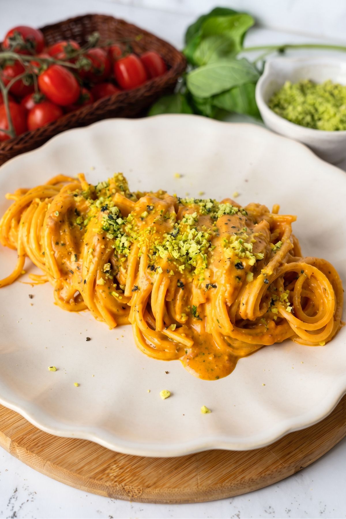 Spaghetti with roasted cherry tomato sauce on a plate and topped with green Parmesan cheese.