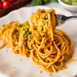 Spaghetti with roasted cherry tomato sauce on t twirled on a fork and topped with green Parmesan cheese.